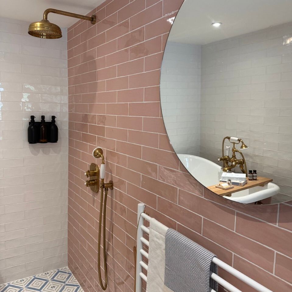 wet room with gold fixtures with pink and white wall tiles